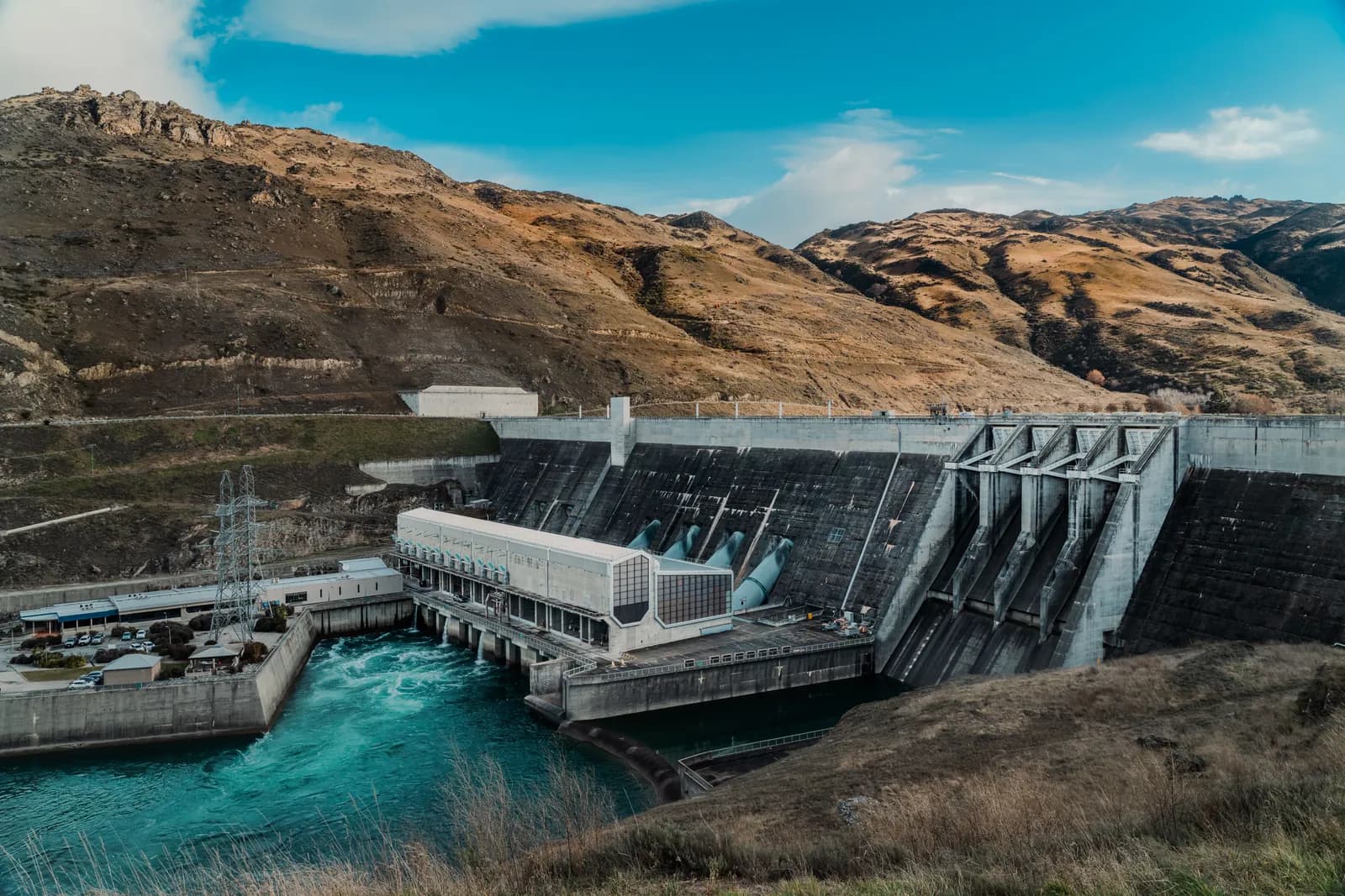 Ein Staudamm und Wasserkraftwerk in einer Hügellandschaft